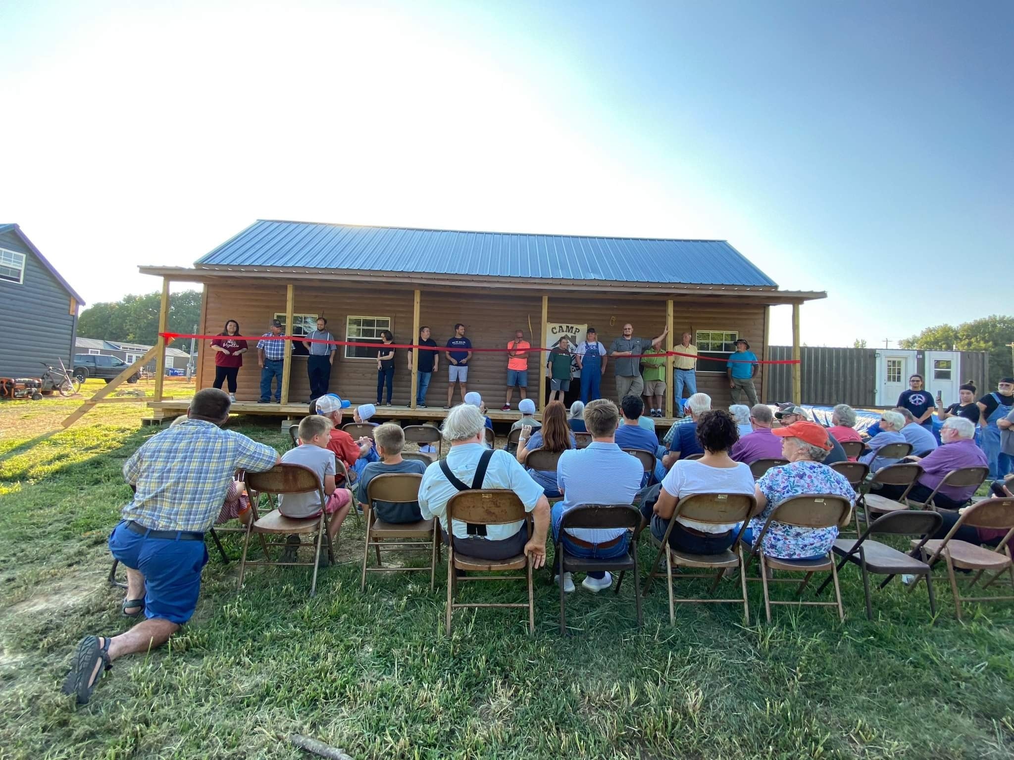 a ribbon cutting ceremony for camp graves held in front of a building
